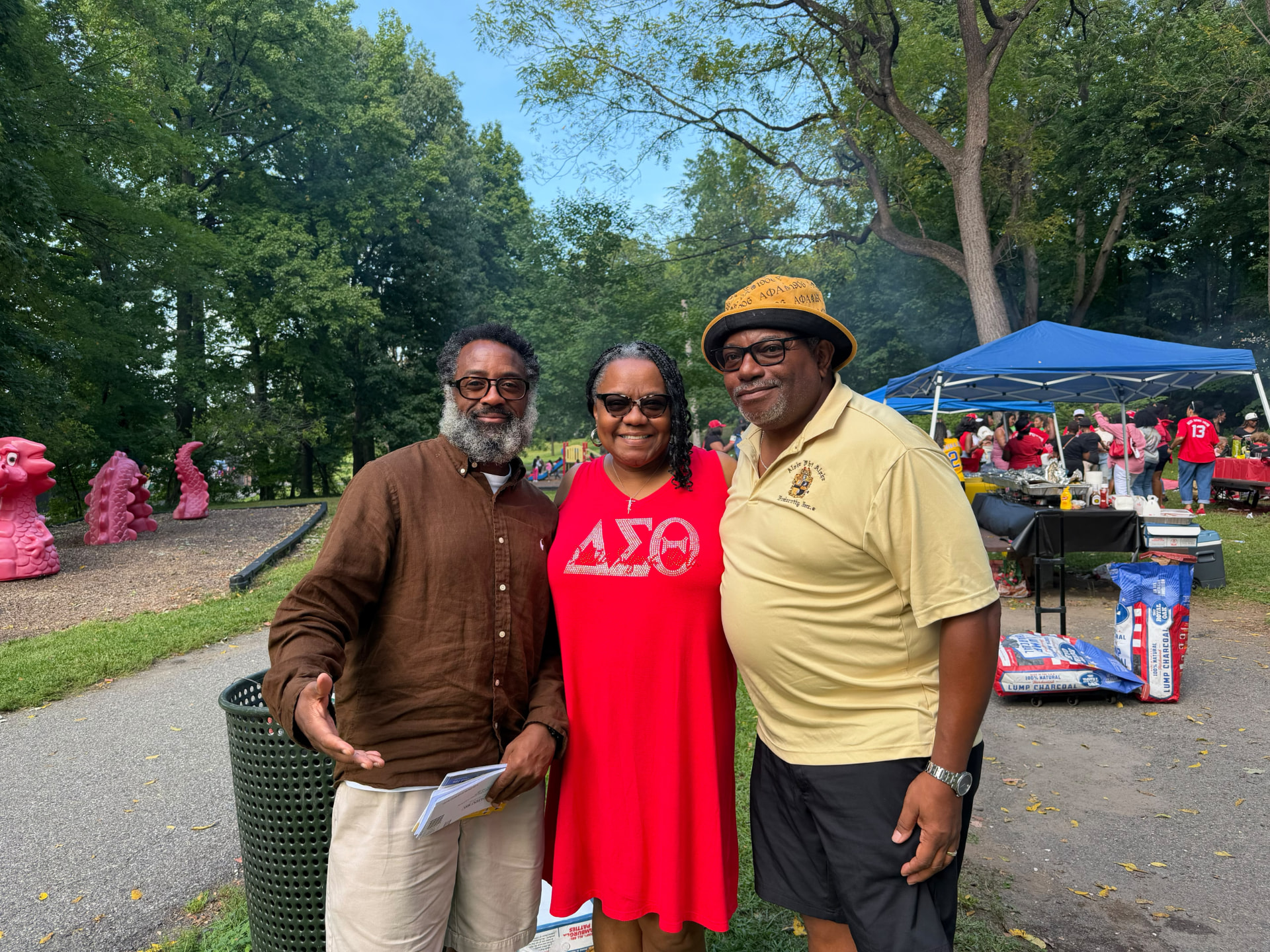 Three community leaders smiling at the outdoor event